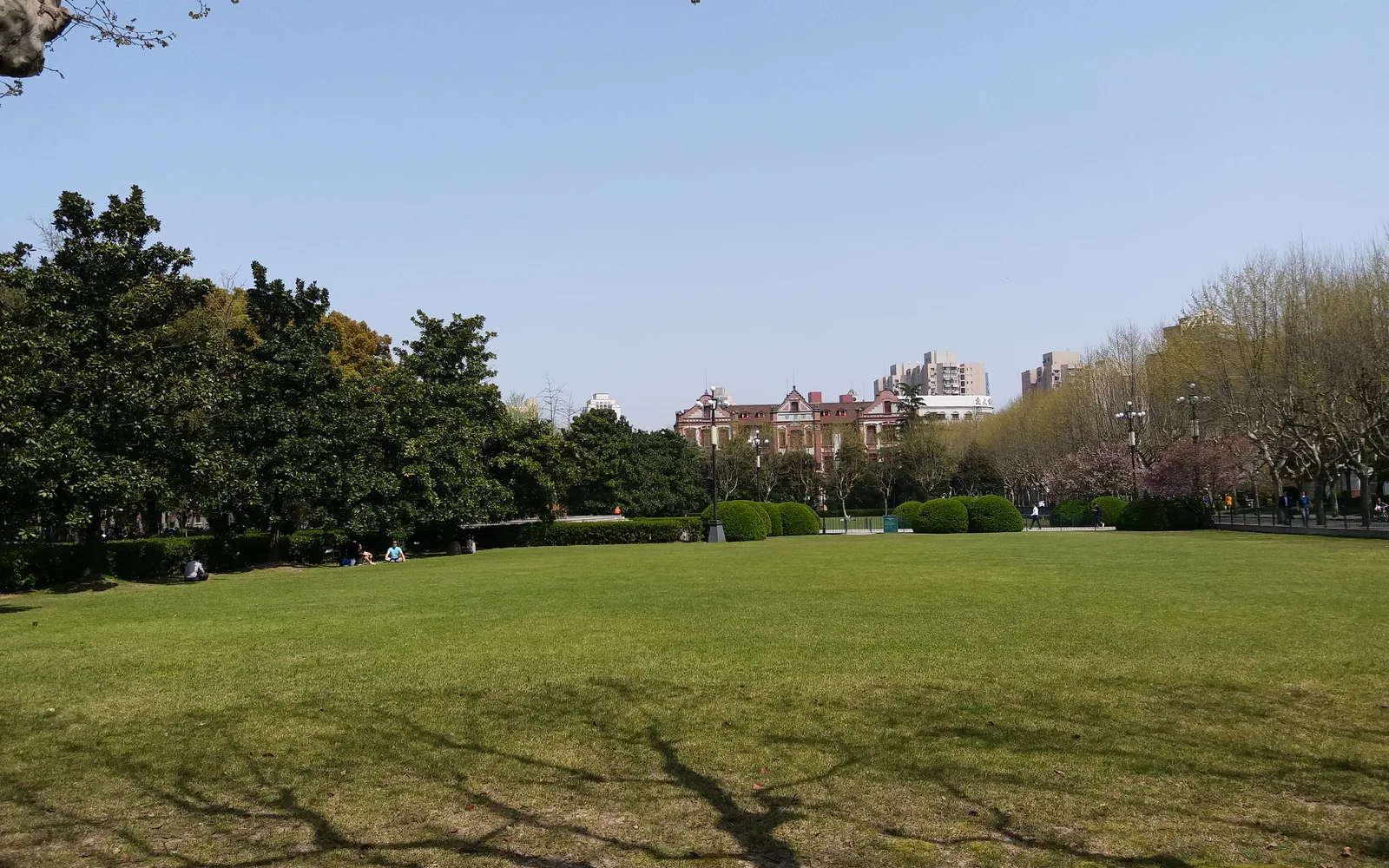 A campus quad with academic buildings, landscaped pathways, and a diverse student population representing a modern urban university